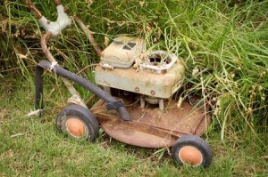 Rusty broken push lawn mower in grass.