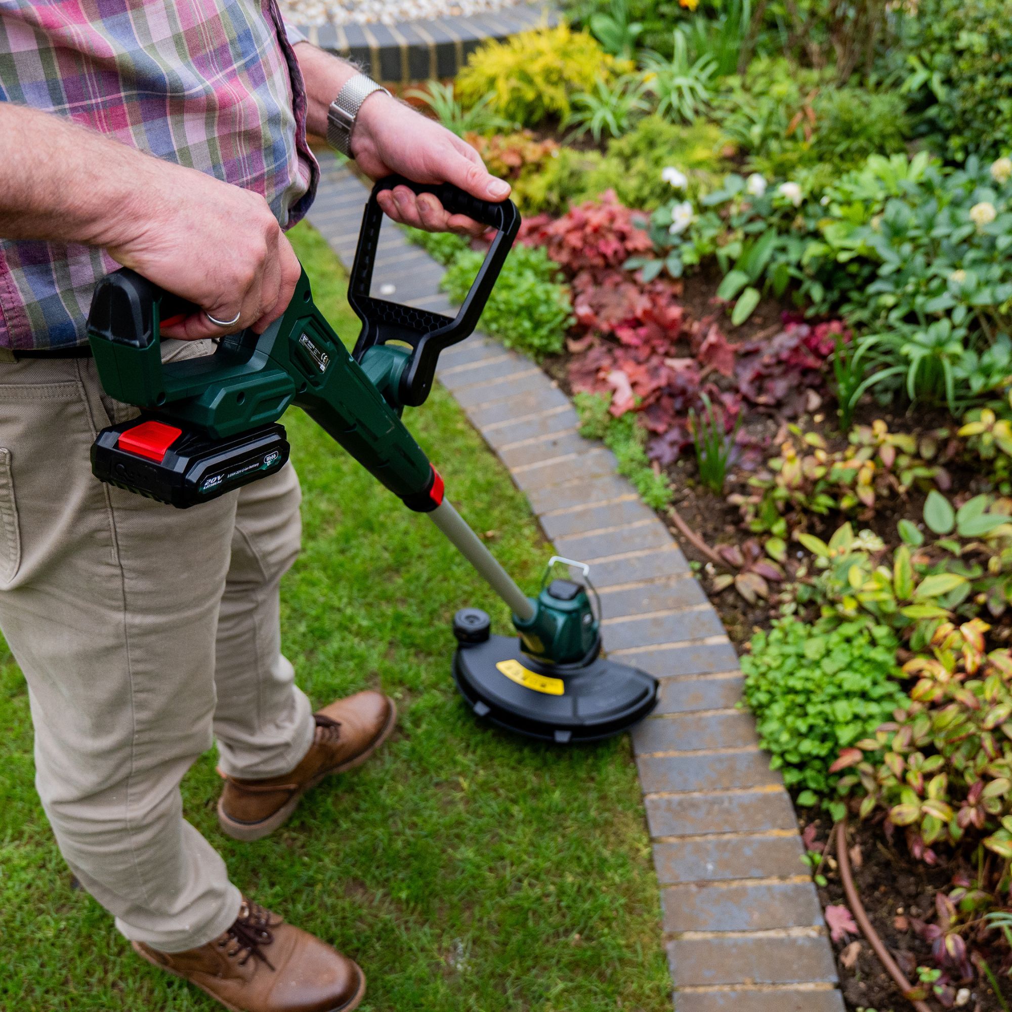 0g5logmic0f.jpg - Mowers Online Man using electric string trimmer along brick edging