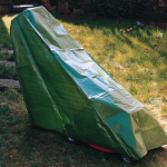 Green boat with white cover on grass