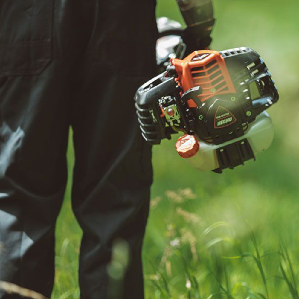 5vbisljayxu.png - Mowers Online Person holding string trimmer over grass