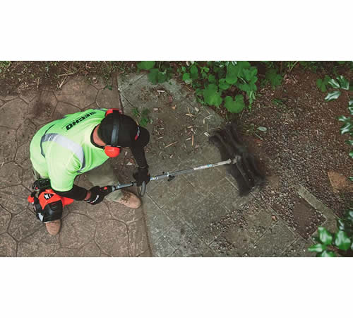 ksbe1bctdel.jpg - Mowers Online Worker operating string trimmer on pavement