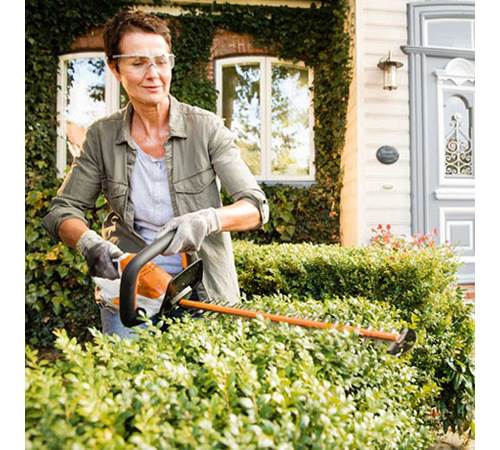ouqo2nzzjdb.jpg - Mowers Online Woman using electric hedge trimmer on shrubs