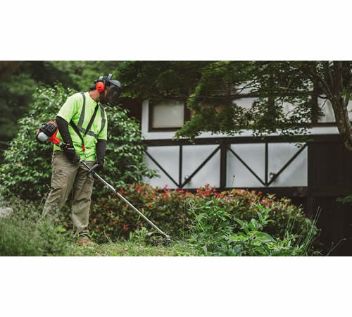 sucyhrprmbu.jpg - Mowers Online Man using string trimmer on grass and weeds
