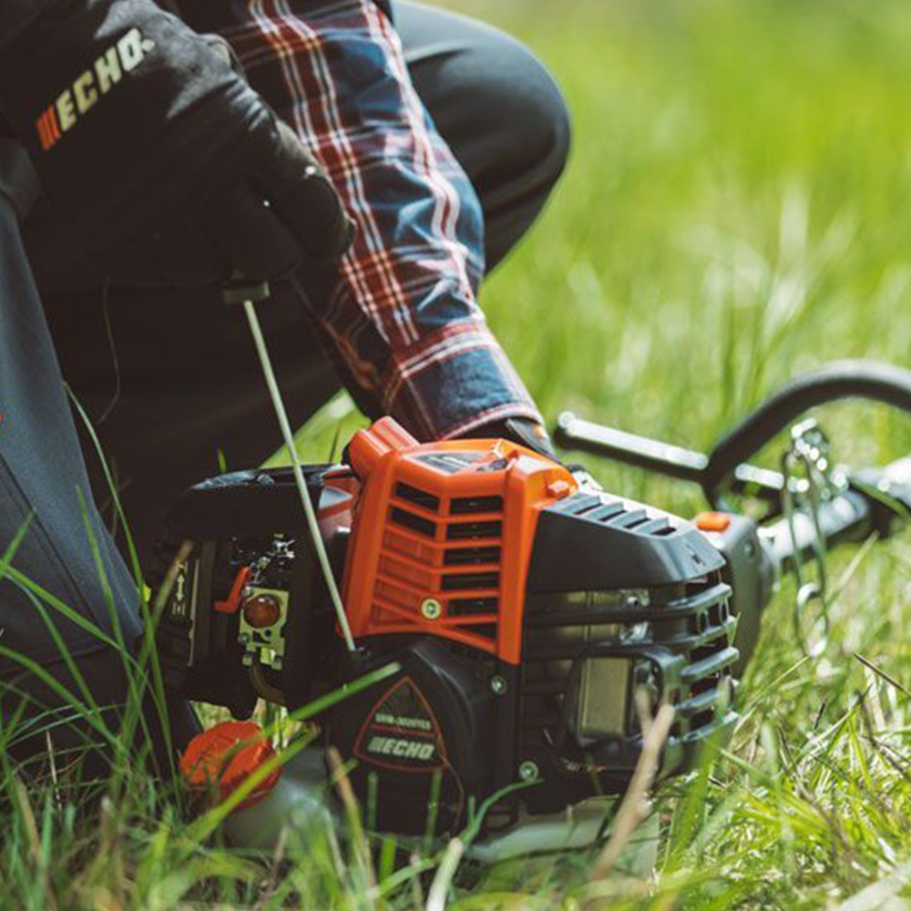 xqpogy33jee.png - Mowers Online String trimmer being held by person in grass